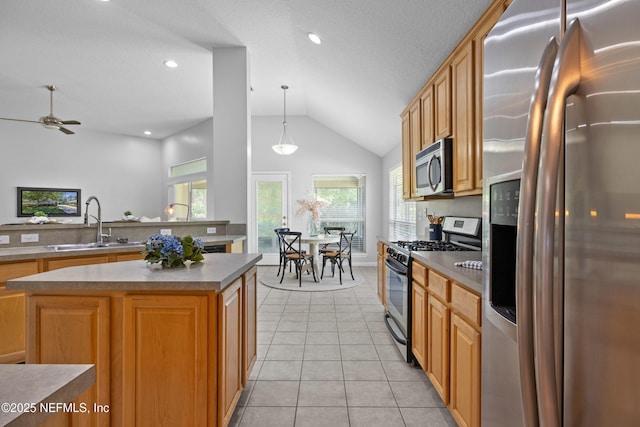 kitchen featuring vaulted ceiling, a sink, light tile patterned floors, ceiling fan, and stainless steel appliances