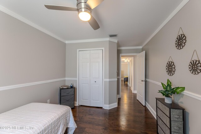 bedroom with wood finished floors, visible vents, ornamental molding, a closet, and ceiling fan
