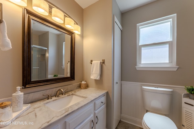full bathroom featuring a wainscoted wall, vanity, an enclosed shower, and toilet