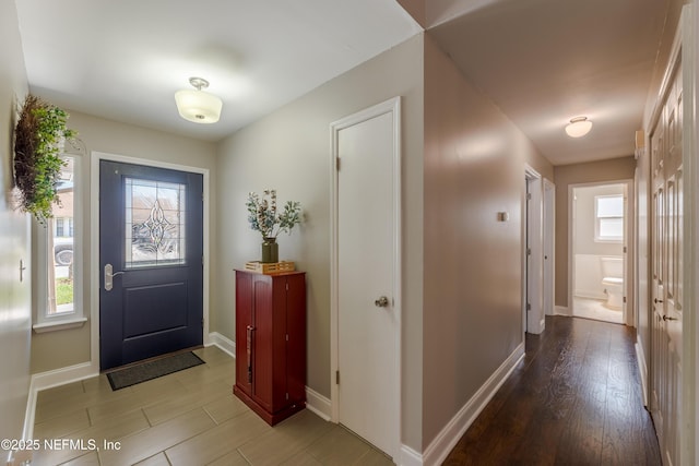 foyer featuring baseboards, a healthy amount of sunlight, and light wood finished floors