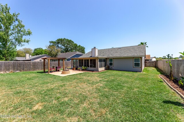 back of house featuring a lawn, a sunroom, a fenced backyard, and an outdoor fire pit