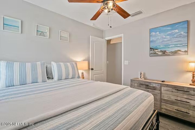 bedroom featuring wood finished floors, a ceiling fan, and visible vents
