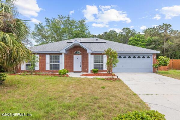 11978 Canterwood Dr, Jacksonville, FL 32246 - ranch-style house with roof mounted solar panels, a front yard, fence, an attached garage, and concrete driveway