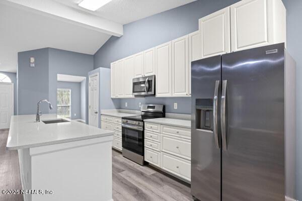 11978 Canterwood Dr, Jacksonville, FL 32246 - kitchen with light wood-type flooring, a sink, white cabinetry, appliances with stainless steel finishes, and vaulted ceiling with beams