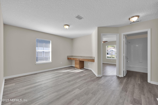 2395 Watermill Dr, Orange Park, FL 32073 - unfurnished living room featuring baseboards, built in study area, a textured ceiling, visible vents, and wood finished floors