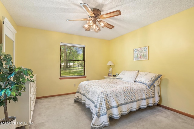 carpeted bedroom with a textured ceiling, baseboards, and a ceiling fan
