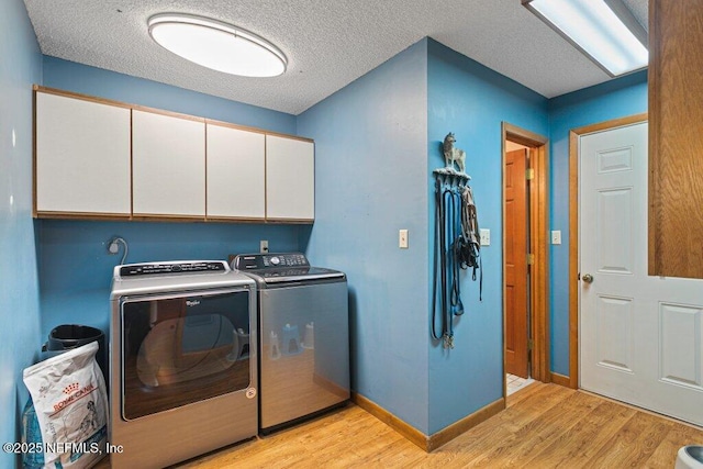 laundry room featuring cabinet space, washing machine and clothes dryer, a textured ceiling, and light wood-style flooring
