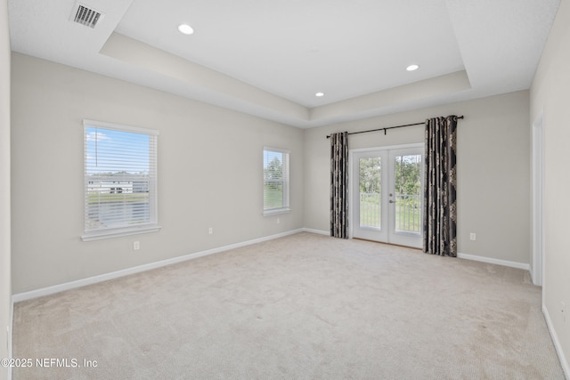 carpeted spare room with recessed lighting, a tray ceiling, visible vents, french doors, and baseboards