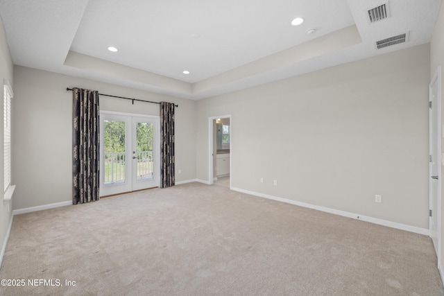 carpeted spare room featuring baseboards, visible vents, and a raised ceiling