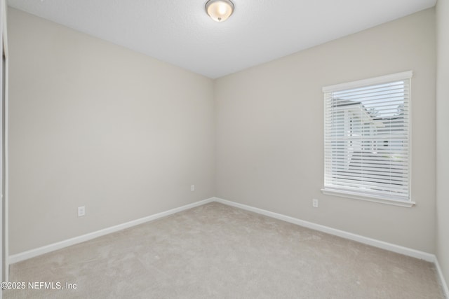 unfurnished room featuring baseboards and light carpet