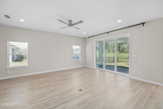 unfurnished room featuring a ceiling fan, visible vents, light wood-style floors, and a healthy amount of sunlight