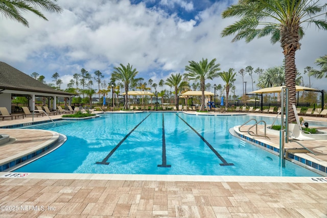 community pool with a patio area and fence