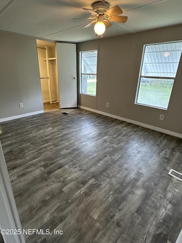 unfurnished bedroom featuring dark wood-type flooring, a closet, baseboards, and visible vents