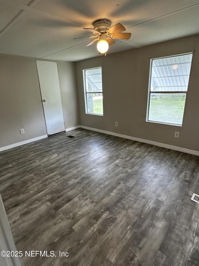 spare room featuring ceiling fan, baseboards, dark wood finished floors, and visible vents
