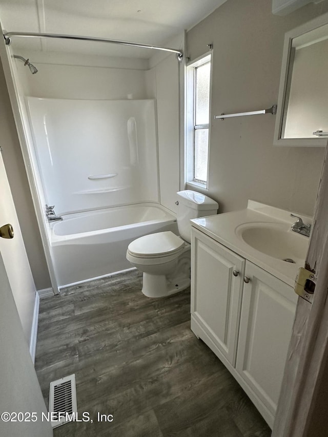 bathroom featuring visible vents, shower / washtub combination, toilet, vanity, and wood finished floors