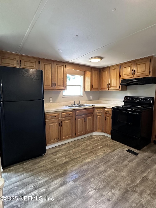 kitchen featuring a sink, light countertops, black appliances, and under cabinet range hood
