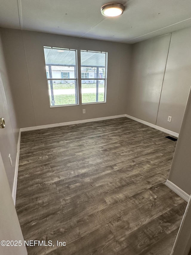 empty room with dark wood-style flooring, baseboards, and a healthy amount of sunlight