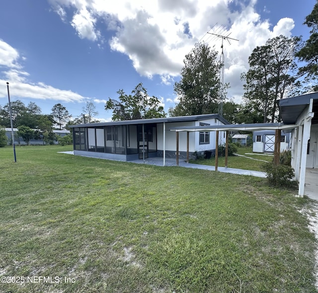 back of property with a yard, an attached carport, and a sunroom