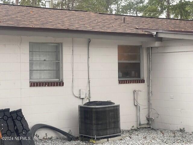 4123 Piper Dr, Jacksonville, FL 32207 - view of side of home with central air condition unit, a shingled roof, and concrete block siding