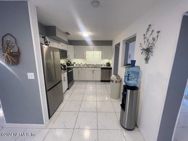 4123 Piper Dr, Jacksonville, FL 32207 - kitchen with baseboards, visible vents, stainless steel appliances, marble finish floor, and a sink