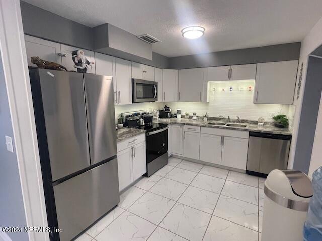 4123 Piper Dr, Jacksonville, FL 32207 - kitchen featuring white cabinetry, visible vents, appliances with stainless steel finishes, marble finish floor, and a sink