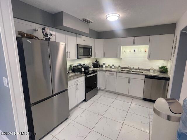4123 Piper Dr, Jacksonville, FL 32207 - kitchen featuring visible vents, white cabinets, a sink, stainless steel appliances, and marble finish floor