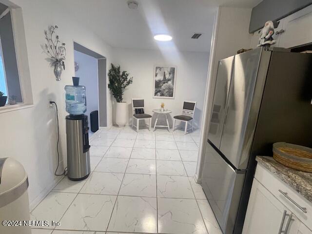 4123 Piper Dr, Jacksonville, FL 32207 - kitchen featuring visible vents, white cabinets, freestanding refrigerator, light stone countertops, and marble finish floor