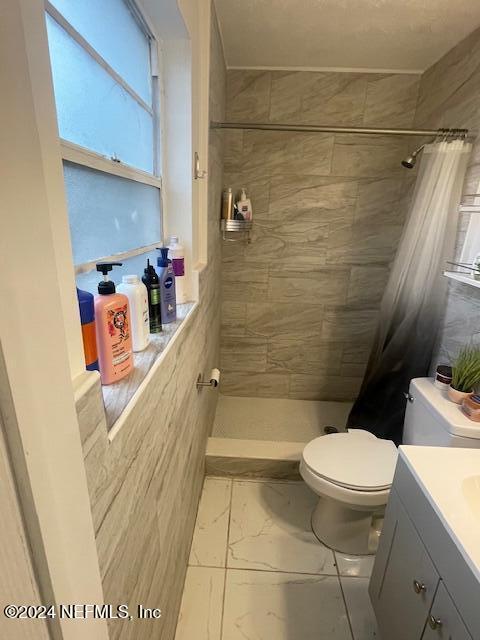 4123 Piper Dr, Jacksonville, FL 32207 - bathroom featuring toilet, tiled shower, marble finish floor, and vanity