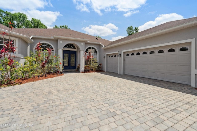 1542 Wescott Loop, Winter Springs, FL 32708 - view of front facade featuring stucco siding, an attached garage, decorative driveway, and french doors