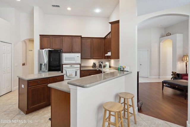 1542 Wescott Loop, Winter Springs, FL 32708 - kitchen with white appliances, a high ceiling, a breakfast bar area, and light tile patterned flooring