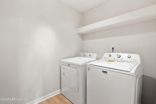 laundry area featuring washer and clothes dryer, light wood finished floors, laundry area, and baseboards