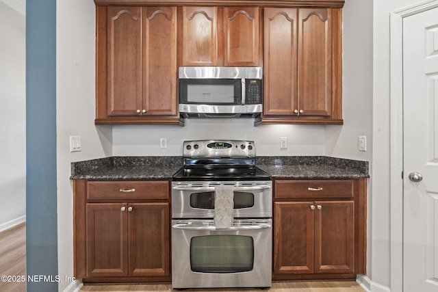 kitchen featuring dark stone countertops, baseboards, and appliances with stainless steel finishes