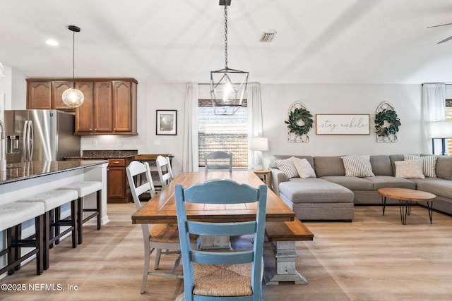 dining area with light wood finished floors, a ceiling fan, and visible vents