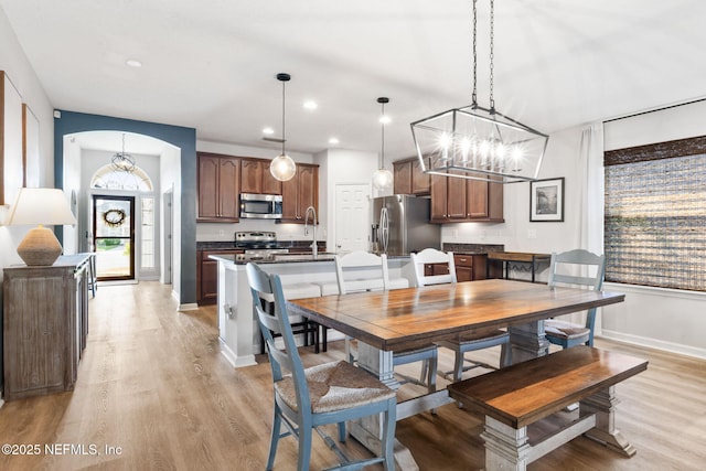 dining area featuring baseboards, an inviting chandelier, recessed lighting, light wood-style floors, and arched walkways