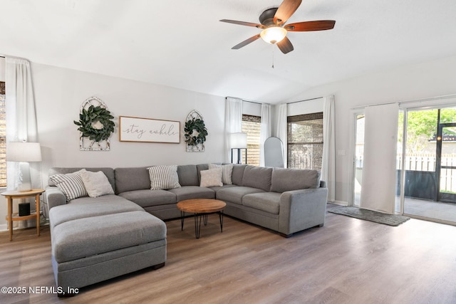 living area featuring light wood-style floors, a ceiling fan, and vaulted ceiling