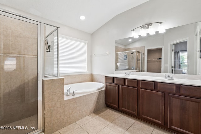 bathroom featuring a garden tub, tile patterned flooring, vaulted ceiling, a stall shower, and double vanity