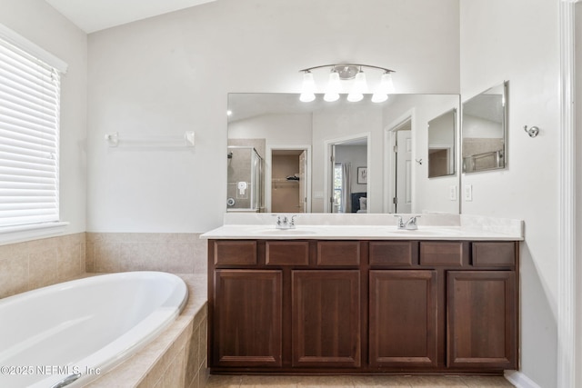 bathroom featuring a bath, a sink, double vanity, and a stall shower