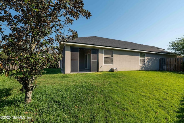 rear view of house featuring fence and a lawn