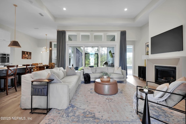 52 Sunshine Bass Ct, Ponte Vedra, FL 32081 - living area with a tray ceiling, visible vents, light wood-style flooring, and a glass covered fireplace