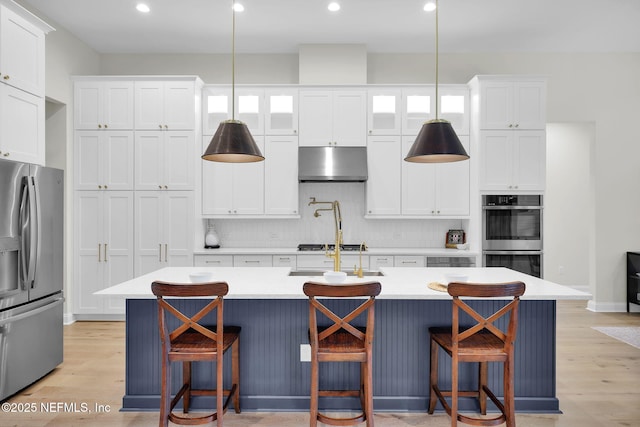 52 Sunshine Bass Ct, Ponte Vedra, FL 32081 - kitchen with under cabinet range hood, appliances with stainless steel finishes, white cabinetry, and a center island with sink