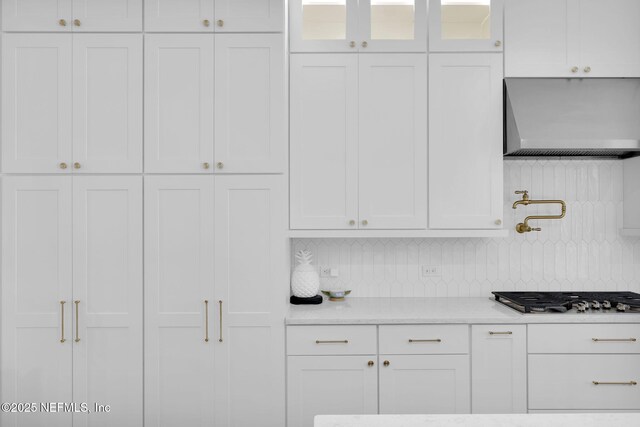 52 Sunshine Bass Ct, Ponte Vedra, FL 32081 - kitchen featuring wall chimney range hood, white cabinetry, decorative backsplash, glass insert cabinets, and stainless steel gas cooktop