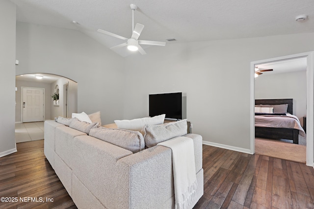 living area with dark wood-style flooring, visible vents, ceiling fan, high vaulted ceiling, and arched walkways