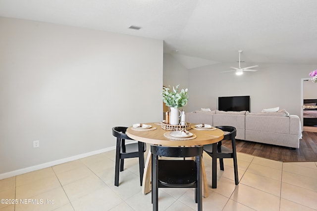 dining room with ceiling fan, visible vents, vaulted ceiling, light tile patterned flooring, and baseboards