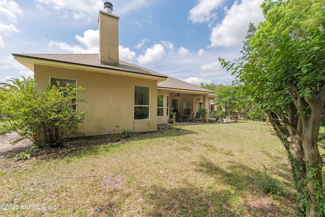 13772 Chipperfield Ln, Jacksonville, FL 32226 - rear view of property with a chimney, a patio area, ceiling fan, a yard, and stucco siding