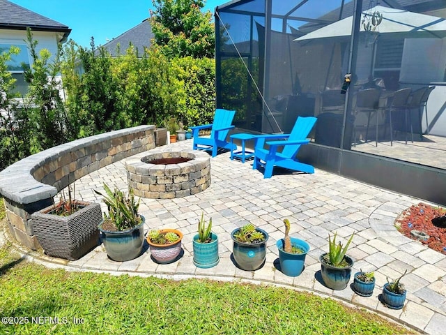 view of patio featuring a fire pit and glass enclosure