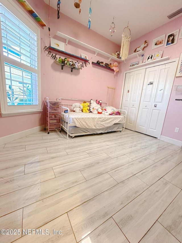 bedroom with a closet, light wood-style floors, and baseboards