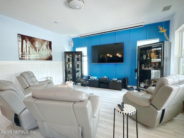 living room featuring visible vents, plenty of natural light, and a decorative wall