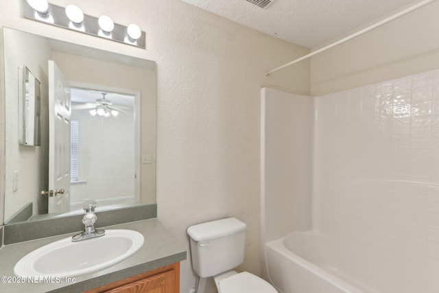 bathroom featuring a textured ceiling, toilet, ceiling fan, a textured wall, and vanity