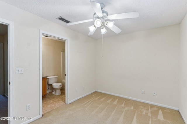 unfurnished bedroom featuring visible vents, a ceiling fan, light carpet, baseboards, and ensuite bathroom