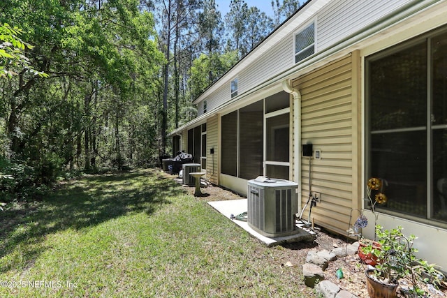 view of yard featuring central air condition unit and a sunroom